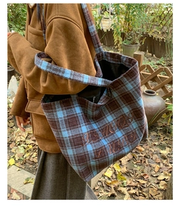 Close-up of blue and brown plaid wool tote bag with embroidered letters on the side