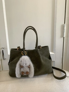 Minimalist olive green suede tote bag with round handles and grey rabbit charm accessory
