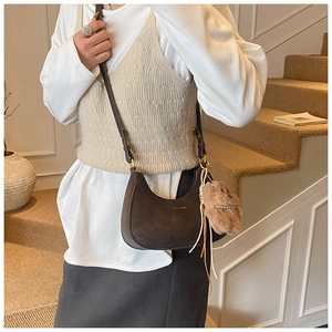 Detail of dark brown retro saddle bag with matte finish and plush bear accessory