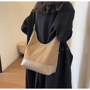Detail of beige suede and leather hobo bag worn with a black coat for office styling