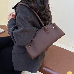 Detail of dark brown lychee leather texture and silver buckle on a baguette bag