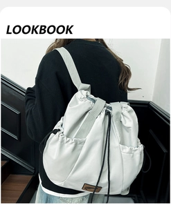 Close-up of lightweight grey drawstring backpack with leather patch and side pockets