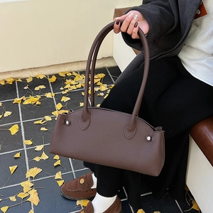 Detail of dark brown pebble texture shoulder bag with metallic rivets and slim straps