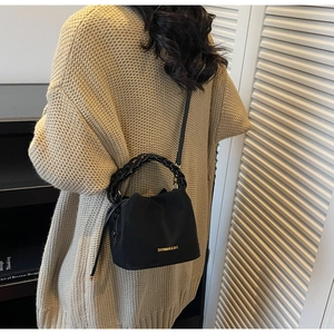 Detail of black matte bucket bag with thick woven handle and gold brand logo