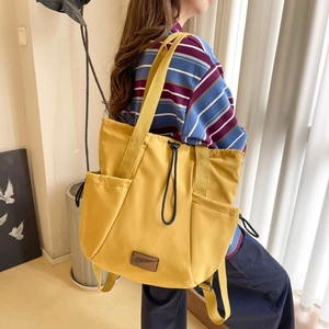Detail view of yellow drawstring backpack showing versatile straps and side storage pockets