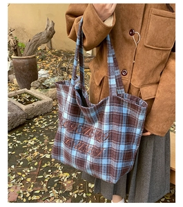 Detailed view of vintage plaid pattern and brown embroidery on a large tote bag