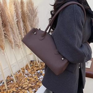 Detail view of dark brown pebbled leather shoulder bag with minimalist silver studs