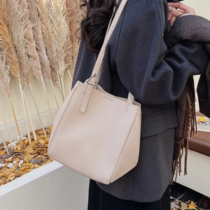 Detail of minimalist beige leather tote with geometric folding and silver metal hardware