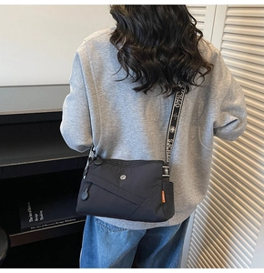 Detail of black square crossbody bag with adjustable SJCHAO letter strap and orange side label