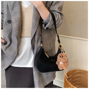 Detail of black crescent hobo bag with gold logo, metal zipper and brown teddy charm
