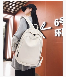 Detailed side view of white faux leather waterproof backpack worn by a student model