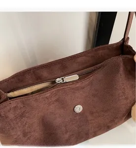 Detail of dark brown suede tote bag featuring smooth silver zipper and magnetic snap closure