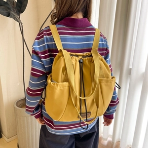 Detail of yellow nylon drawstring backpack with side pockets and leather logo patch