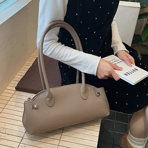 Detail of khaki pebbled leather baguette bag with silver buckle and long handle