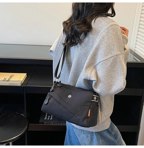 Detail of durable black nylon crossbody bag with side pocket and contrast strap