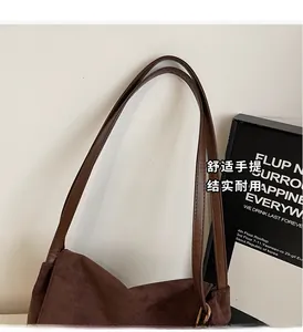 Detail of sturdy brown leather handles and premium stitching on a suede tote bag
