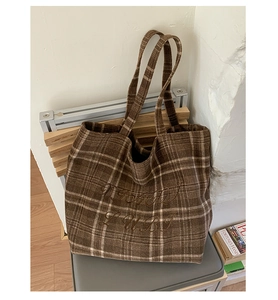 Detail of large brown plaid wool tote bag with embroidered letters and long handles
