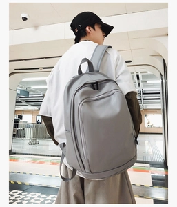 Detail view of a gray waterproof student backpack with large pockets in a subway setting
