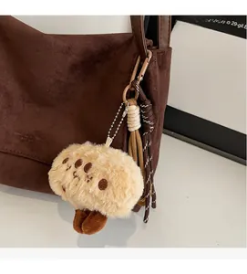 Detail of vintage brown suede tote bag with cartoon plush charm and leather handle strap