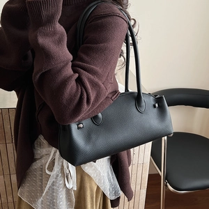 Detail of black lychee-textured leather shoulder bag with silver studs on model
