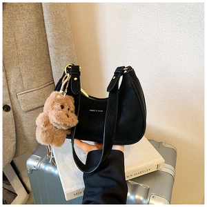 Close-up of black leather underarm bag with cute teddy bear charm and gold metal zipper