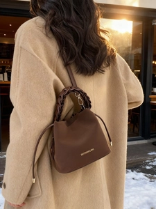 Brown suede bucket bag with woven handle shown in a snowy outdoor winter setting