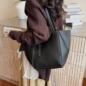 Detail of black pebbled leather tote bag with white contrast stitching and slim straps