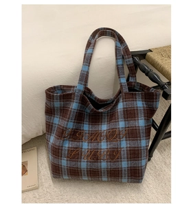 Detail of blue and brown plaid wool tote bag with premium embroidered lettering and texture