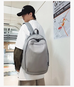 Deep grey waterproof backpack worn by a male model in a modern urban transit setting