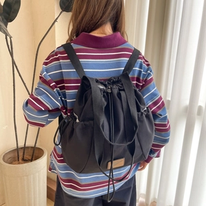 Close-up of black multifunctional drawstring backpack with waterproof nylon and side straps