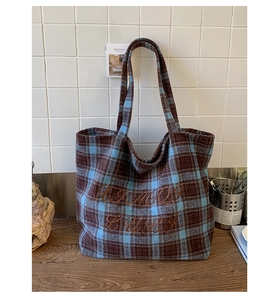 Close-up of vintage plaid embroidery on a large tote bag with autumn texture