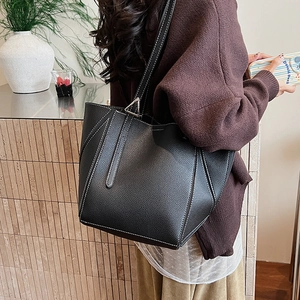 Detail of black leather tote bag featuring white contrast stitching and silver hardware