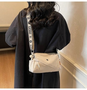 Detail of cream crossbody bag featuring layered zippers and SJCHAO decorative wide strap