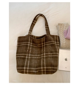 Detail of vintage brown plaid tote bag with artistic embroidery on wool-like fabric texture