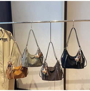 Detail view of four multi-color retro hobo bags with bear charms hanging on a metal rack