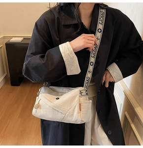 Detail of off-white crossbody bag with multi-pocket design and wide pattern strap