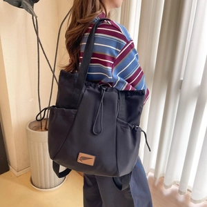 Detail view of black waterproof nylon tote bag with drawstring closure and side pockets