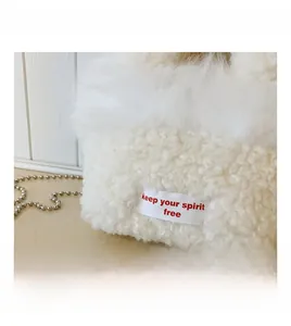 Detail of white fuzzy fleece handbag with red keep your spirit free embroidered label