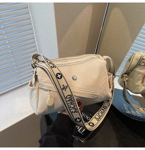 Close-up of beige crossbody bag with wide jacquard strap and zipper compartments