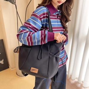 Close-up of black multifunctional drawstring tote bag with brown leather brand logo patch