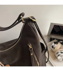 Detail of dark brown leather handbag featuring gold metal rings and adjustable strap