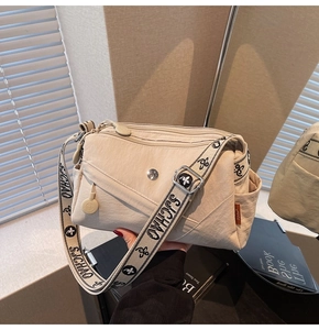 Detail shot of beige nylon crossbody bag with floral printed strap and zip pockets
