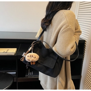 Close-up of a black Hobo bag with a metal buckle and a cute brown plush pendant detail