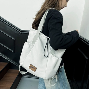 Close-up of white nylon tote bag with side pocket and brown leather logo patch
