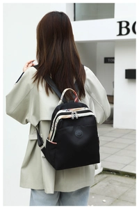 Close-up of black oxford backpack featuring floral pattern accents and rubber brand logo