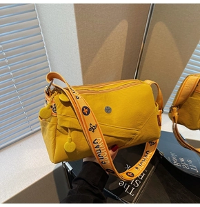 Detailed close-up of a yellow nylon crossbody bag featuring stylish embroidered wide straps