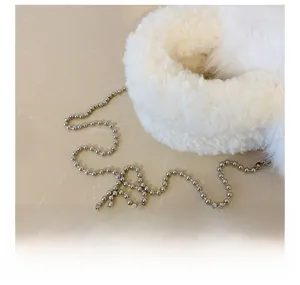 Close-up of fluffy faux fur texture and elegant silver bead chain on a shoulder bag
