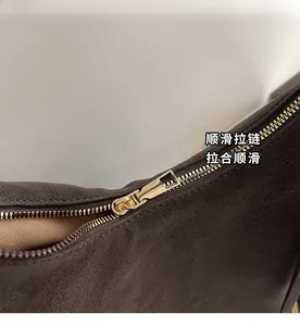Detail of premium smooth gold zipper on a high-quality brown suede leather handbag