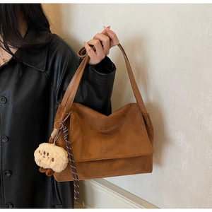 Detail of vintage brown faux suede tote bag with plush charm and shoulder strap