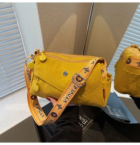 Detail of yellow nylon crossbody bag with floral embroidered wide strap and multi-layer zippers